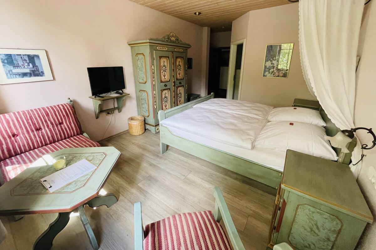 Una habitación con una cama, televisión, cómoda y una mesa con una silla.