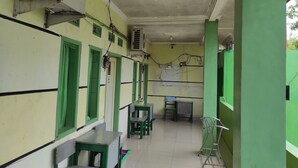 A corridor with green-framed windows, a ceiling fan, and a green pillar. - OYO 90333 Wisma Tenang Jaya Syariah (Jatiwangi)