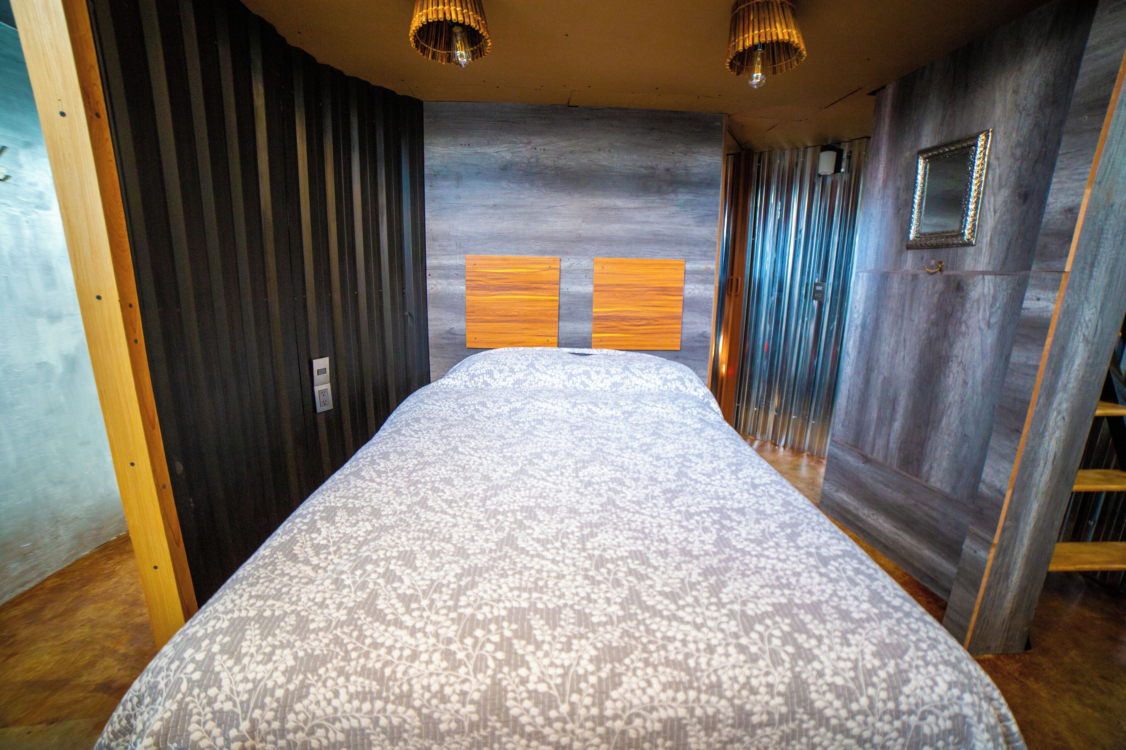 A bedroom with a bed, wooden walls, and a sloped ceiling.