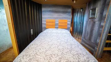 A bedroom with a bed, wooden walls, and a sloped ceiling.