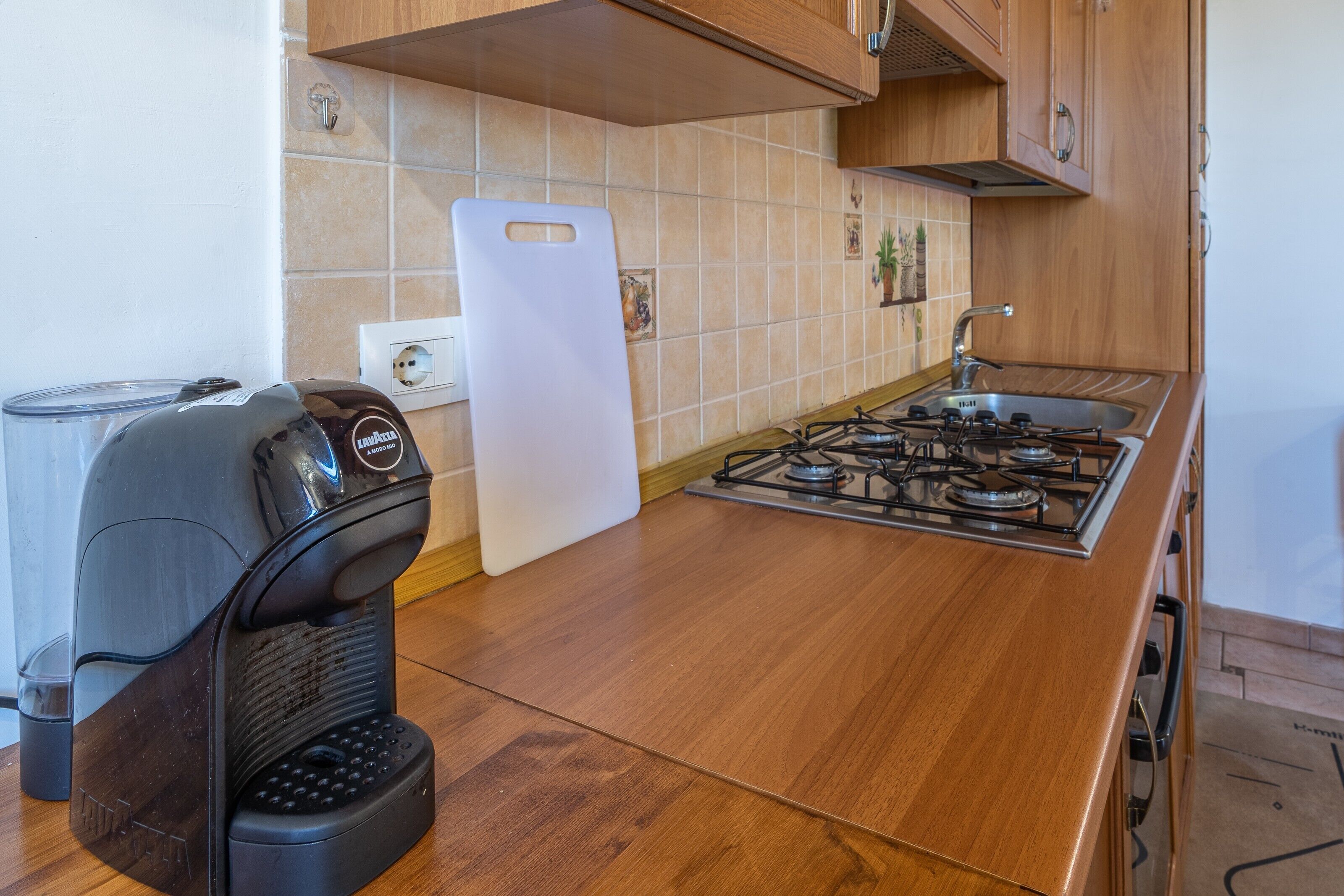 A kitchen with a gas stove, a coffee maker, and a cutting board.