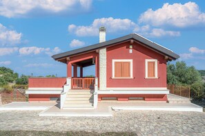 A red building with a covered porch, a chimney, and a stone-paved entrance.