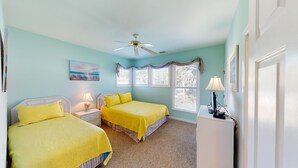 A bedroom with two beds, a ceiling fan, a painting, and a window with curtains. - Beautiful 2BR 2BA Lakeside Villa with Lake Views (Pawleys Island)