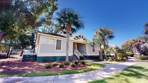 A single-story house with a front porch, a staircase leading to the entrance, and a well-maintained lawn. - Beautiful 2BR 2BA Lakeside Villa with Lake Views (Pawleys Island)