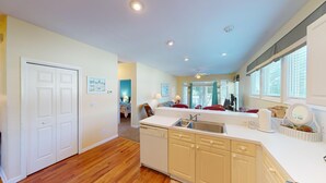 A compact kitchen with a dishwasher, a sink, and a dining area with a table and chairs. - Beautiful 2BR 2BA Lakeside Villa with Lake Views (Pawleys Island)