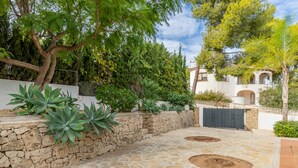 A courtyard with stone flooring, a stone wall, and various plants. - Villa 'La Boniquesa Bajo' with Sea View, Wi-Fi and Air Conditioning (Benissa)