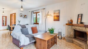 A living room with a sofa, a wooden coffee table, a fireplace, and a dining area with a table and chairs. - Villa 'La Boniquesa Bajo' with Sea View, Wi-Fi and Air Conditioning (Benissa)