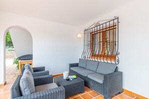 Ein Zimmer mit Korbmöbeln, einem Fenster mit Gitterstäben und einem Fliesenboden.