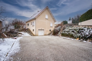 A two-story house with a sloped roof, a front entrance, and a driveway leading to the house.
