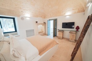 Un dormitorio con cama, televisión, chimenea de piedra y ventana.