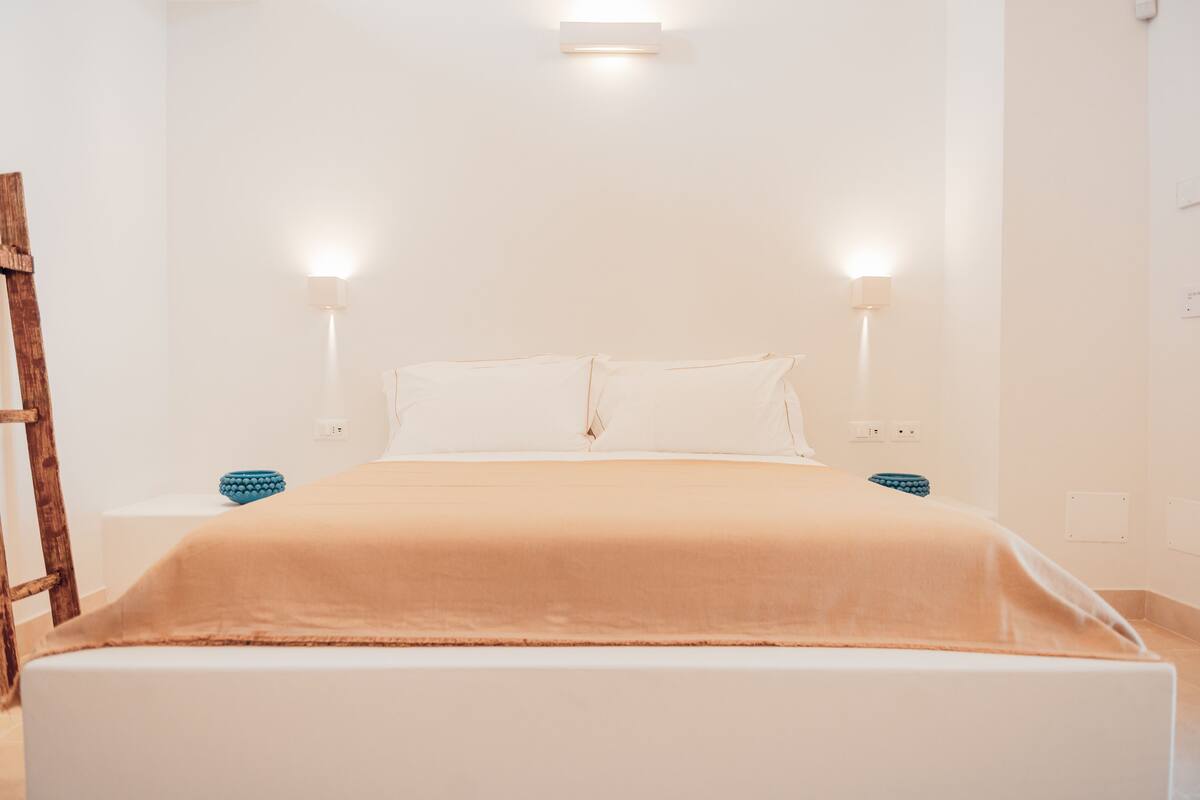 Un dormitorio minimalista con cama, lámparas de noche y una escalera de madera.