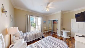 A bedroom with two beds, a ceiling fan, a TV, and a window with curtains. - Escape to Green Haven a Golfer's Delight (Pawleys Island)