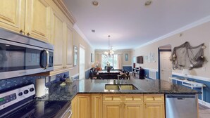 A kitchen with a central island, a microwave, and a refrigerator. - Escape to Green Haven a Golfer's Delight (Pawleys Island)