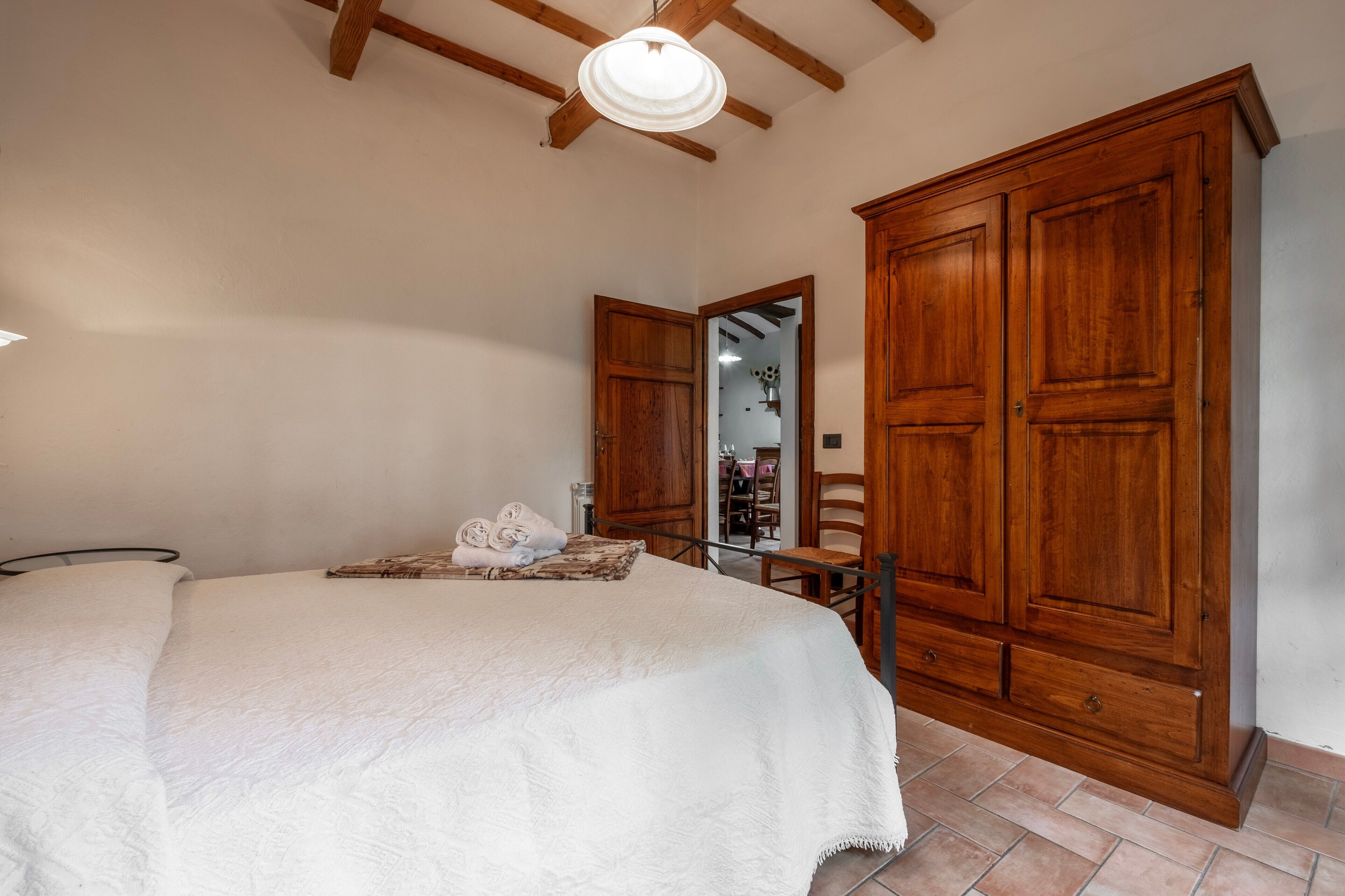 A bedroom with a bed, wooden wardrobe, and a mirror.