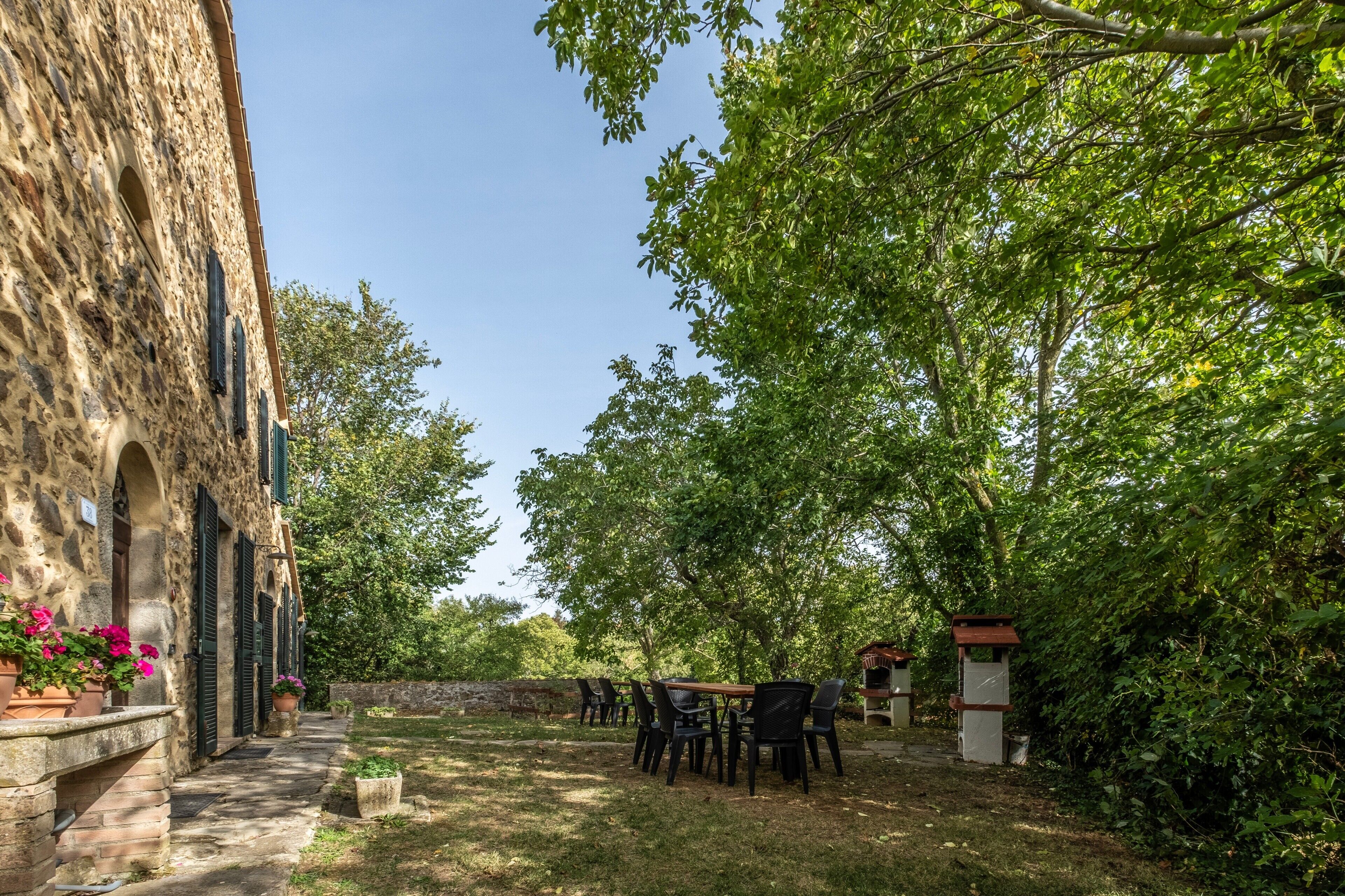 A stone building with a courtyard, outdoor seating, and a small structure.