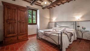 A bedroom with a bed, wooden wardrobe, and a window. - "Ginestra" Apartment in Farmhouse with Shared Pool, Mountain View, and Wi-Fi (Arcidosso)