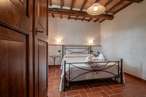 A bedroom with a metal bed frame, a small bedside table, a wall-mounted light, and a wooden ceiling. - Farmhouse "Ginestra" with Shared Pool, Private Garden & Wi-Fi (Arcidosso)
