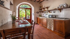 Uma cozinha com armários de madeira, painel de azulejos e um espaço de jantar com mesa e cadeiras.