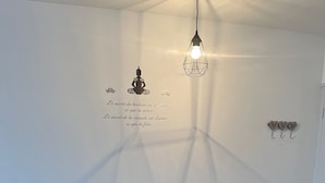 A dining area with a table and chairs, a hanging light fixture, and wall decorations including a silhouette and text.