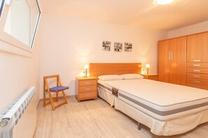 Une chambre à coucher comprenant un lit, des tables de chevet, une chaise, une armoire et un radiateur.