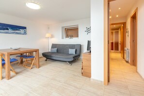 Un salon moderne avec un canapé, une table à manger et des chaises, une lampe et un tableau accroché au mur.