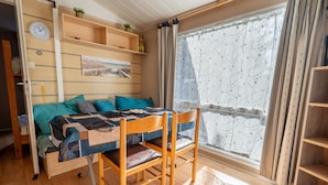 Une pièce confortable avec un lit, une table et des chaises, une horloge et une fenêtre avec des rideaux.