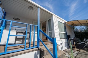 Ein Wohnmobil mit Veranda, Treppe und kleinem Garten.