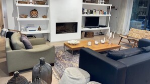 Een moderne woonkamer met een bank, salontafel en planken met decoratieve objecten.