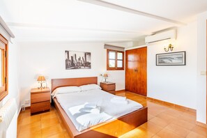 Une chambre d’hôtel équipée d’un lit, de tables de chevet, d’une fenêtre et d’un climatiseur fixé au mur.