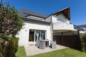 Une maison à deux étages avec un patio, une porte-fenêtre coulissante et une cour arrière clôturée.
