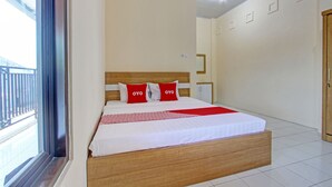 A hotel room with a large bed, a wooden headboard, and a view of the balcony.