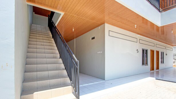 A modern interior with a staircase, a wooden ceiling, and a clean, tiled floor.