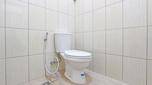 A small, clean bathroom with a toilet, a shower, and a tiled floor.