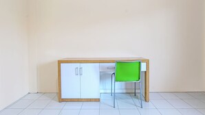 A small, simple room with a wooden desk and a green chair.