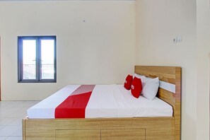 A neatly made bed with a wooden headboard, white bedding, and red accents. A window with a view of a balcony is visible. - Hotel O Mi Casa Inn (Pati)