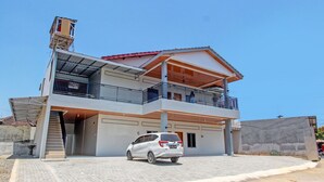 A two-story building with a covered parking area and a white car parked in front.
