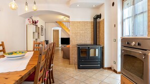 A kitchen with a stove, oven, and dining area with chairs and a table. - Chalet 'Maso Gigi' with Mountain View, Private Garden and Wi-Fi (Ivano fracena)