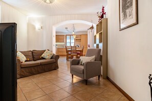 A living room with a sofa, armchair, and dining table.