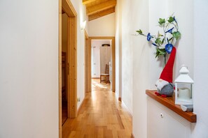 Un pasillo con suelo de madera, una decoración de gnomo y un farol blanco sobre una estantería.
