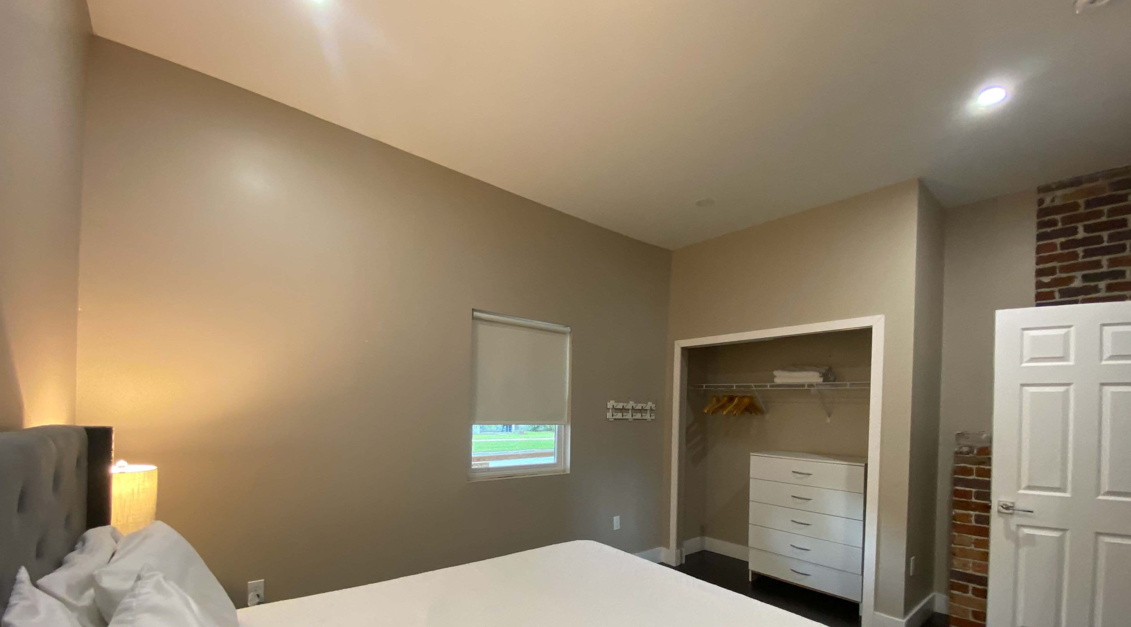 A bedroom with a bed, a wardrobe, a closet, and a window with blinds.
