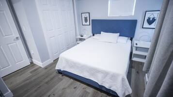 Un dormitorio con cama, mesitas de noche, armario y espejo.