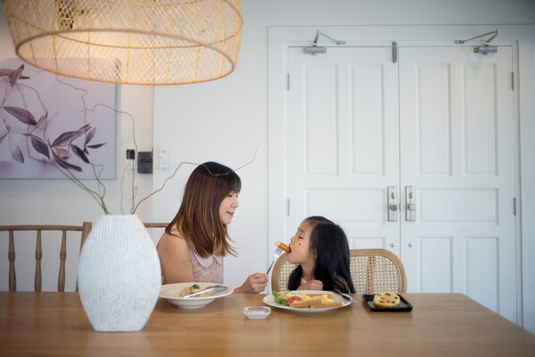 A dining table with plates of food, a white vase, and a wicker chair.