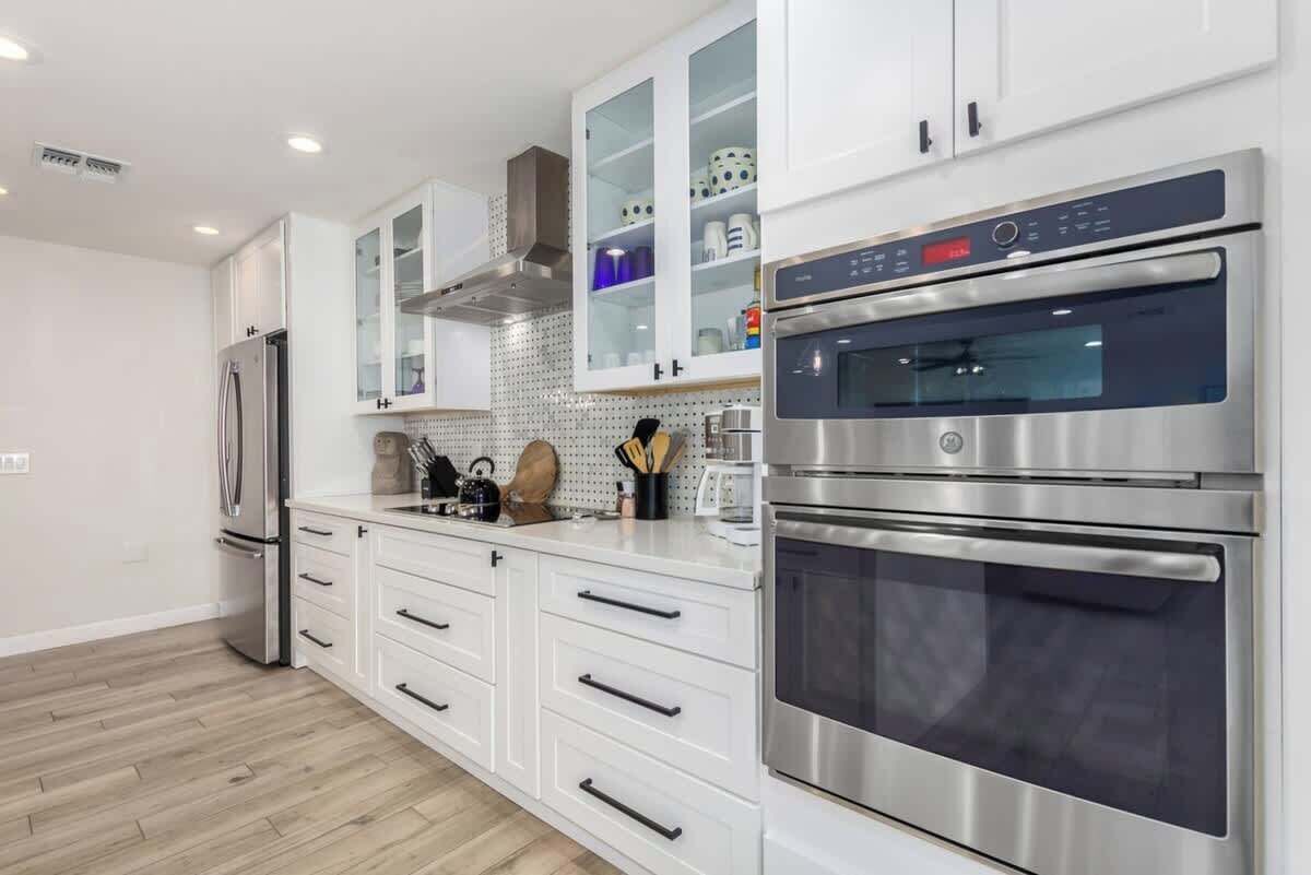 A modern kitchen with white cabinetry, stainless steel appliances, and a tiled backsplash.