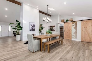 Una habitación amplia con una mesa de madera, bancos y plantas en macetas.