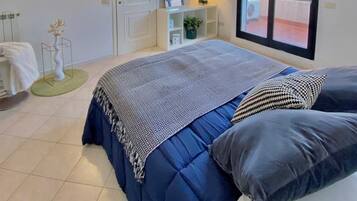 Una camera da letto con un letto grande, una finestra, una porta e un comodino con una lampada.