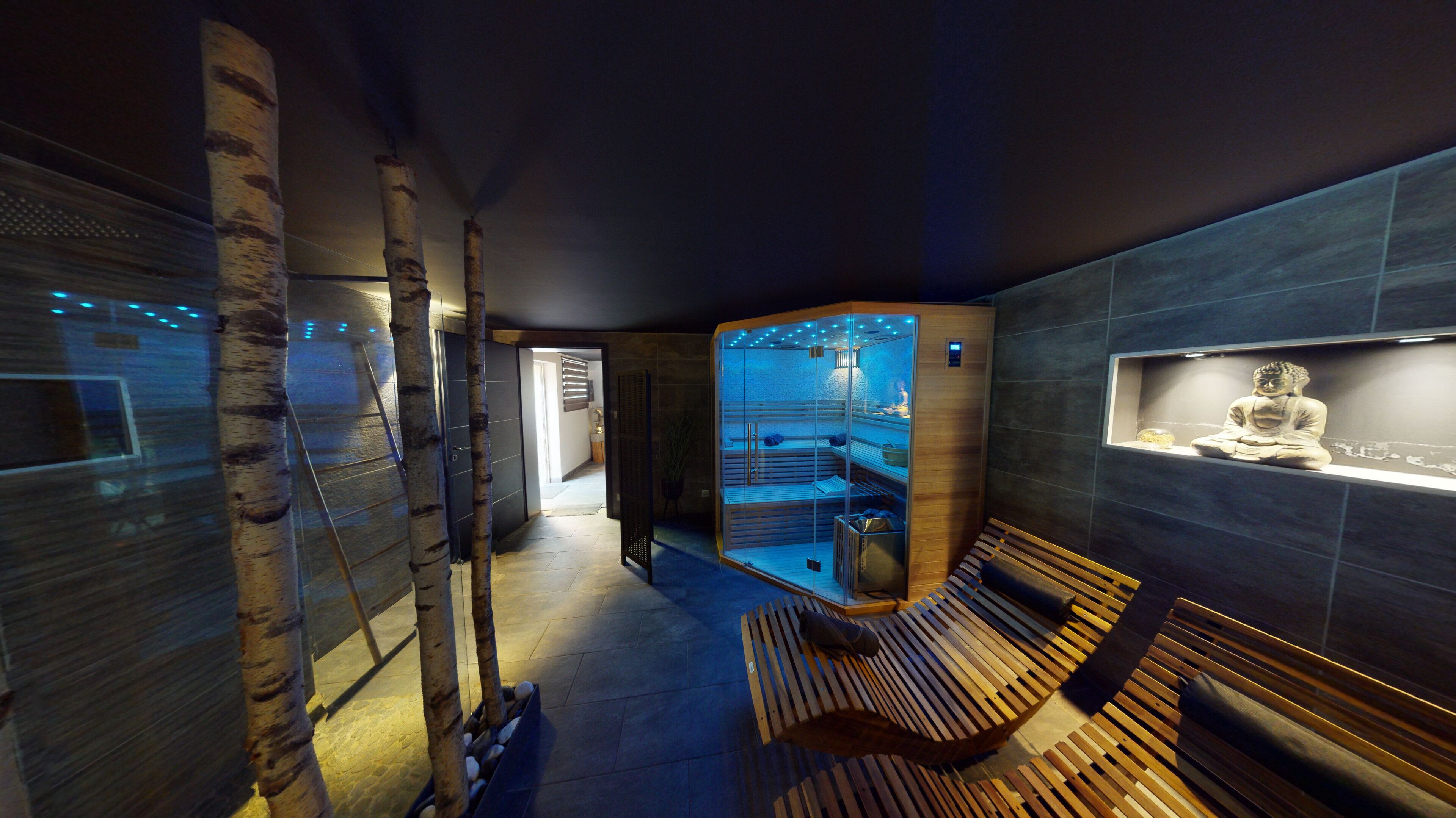 A modern spa area with a wooden bench, a glass sauna, and a Buddha statue.
