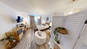Een moderne hotelkamer met een bed, een bureau, een stoel en een televisie.