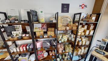 Una tienda con estantes repletos de diversos productos, como frascos, cajas y botellas. Se observan letreros con precios y nombres de los productos.