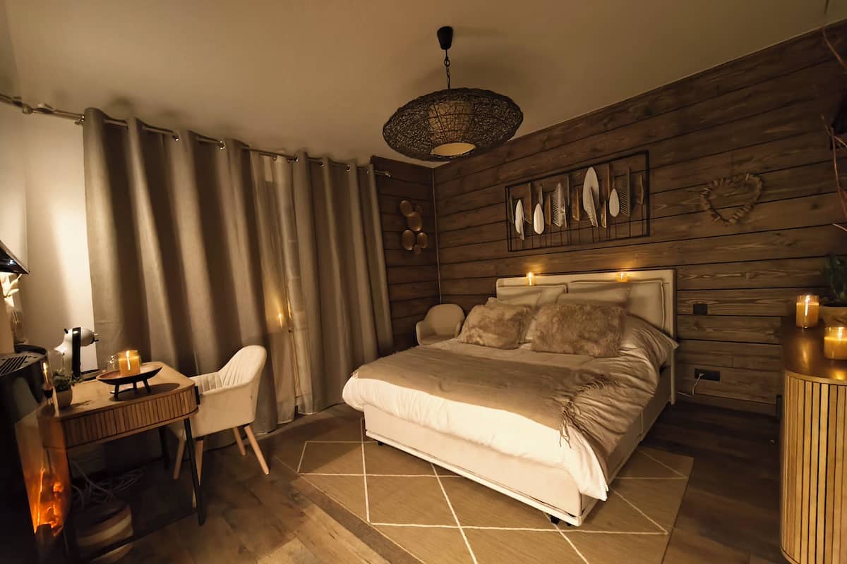 Een slaapkamer met een bed, bureau, stoel en een houten wand met kunst.
