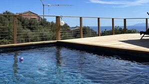 Un ciel d’un bleu éclatant, une terrasse en bois et une piscine.
